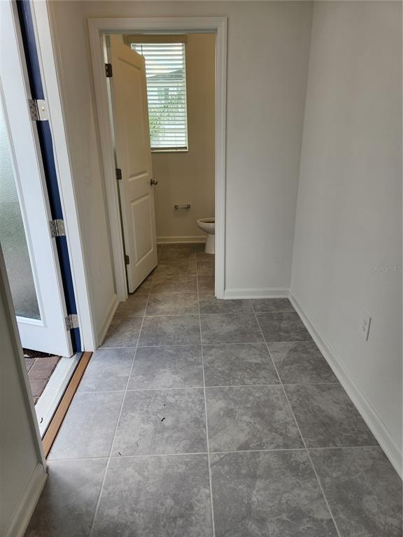 A tiled entryway leads to a doorway revealing a small bathroom with a toilet — 203 BOGEY DRIVE, DAVENPORT, FL