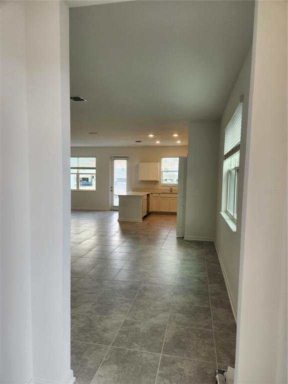 A view from a doorway into an open-concept kitchen and living area with tile flooring — 203 BOGEY DRIVE, DAVENPORT, FL