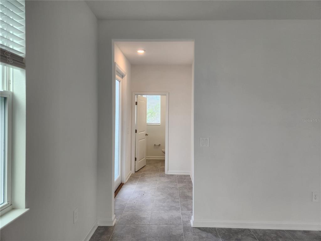 A tiled hallway leads to a doorway revealing a small bathroom with a window — 203 BOGEY DRIVE, DAVENPORT, FL