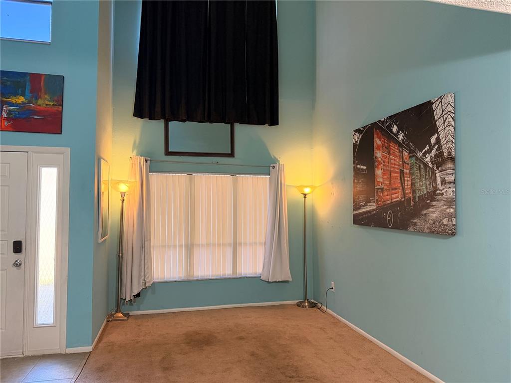A living room with high ceilings, light blue walls, brown carpet, and two floor lamps — 1849 ABRICO DRIVE UNIT K3, LUTZ, FL