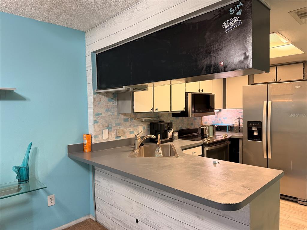 A kitchen features a gray countertop, a corner sink, and a black chalkboard-painted soffit — 1849 ABRICO DRIVE UNIT K3, LUTZ, FL