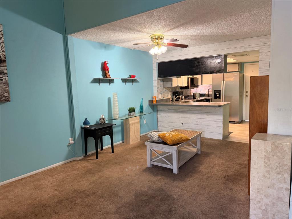 A living room with blue walls, brown carpet, and a kitchen with a breakfast bar — 1849 ABRICO DRIVE UNIT K3, LUTZ, FL