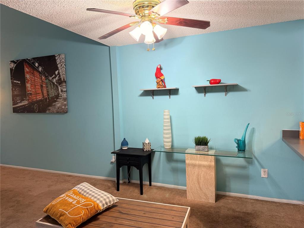 A living room with light blue walls, a ceiling fan, and a glass-topped console table — 1849 ABRICO DRIVE UNIT K3, LUTZ, FL
