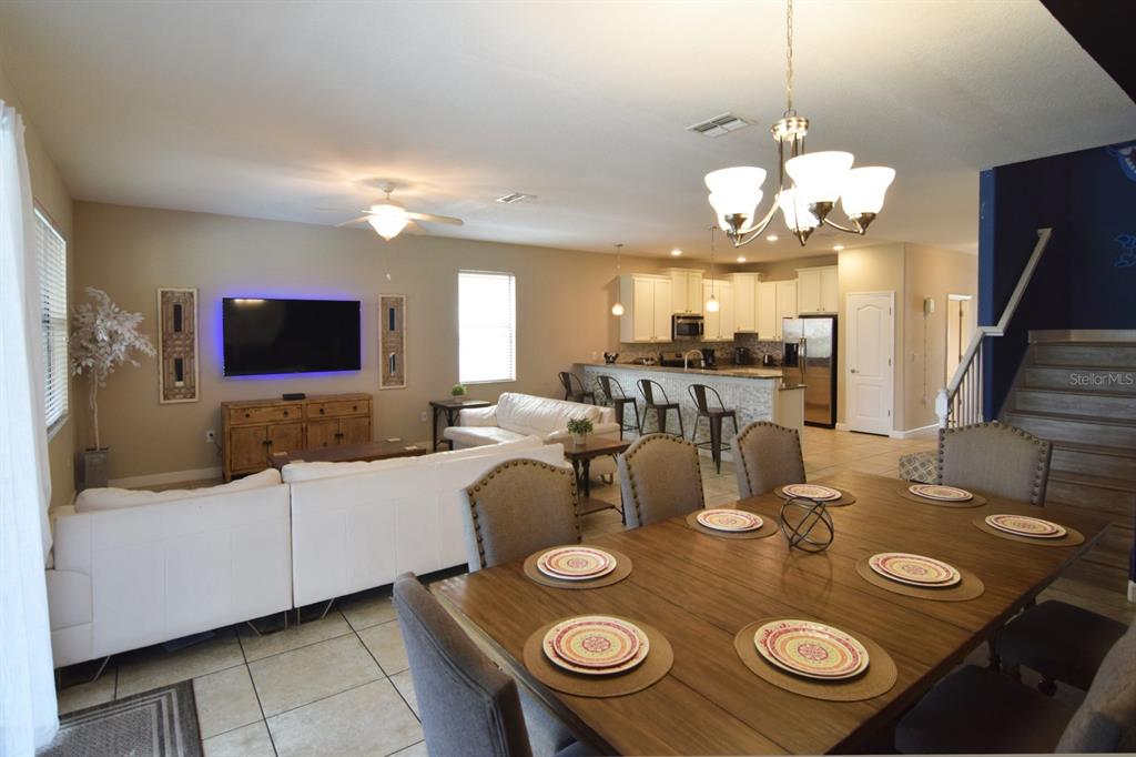 An open-concept living and dining area features tile floors, a kitchen island, and a chandelier — 1402 MOON VALLEY DRIVE, DAVENPORT, FL