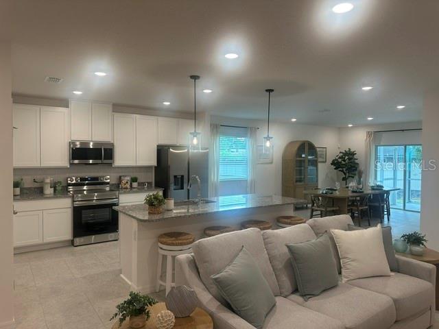 An open-concept kitchen with white cabinets and a breakfast bar overlooks a living area — 1083 WELDA LANE, JACKSONVILLE, FL