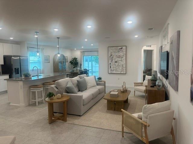 An open-concept living room and kitchen with light tile floors and neutral furniture — 1083 WELDA LANE, JACKSONVILLE, FL