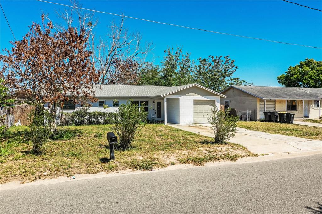 A single-story house with a white exterior, a garage, and a front yard with trees — 1015 CAREFREE COVE DRIVE, WINTER HAVEN, FL
