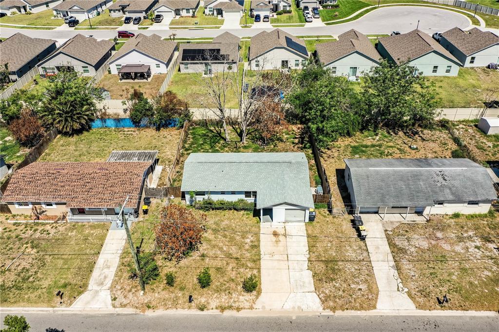 An aerial view shows three single-story houses with driveways and backyards in a suburban neighborhood — 1015 CAREFREE COVE DRIVE, WINTER HAVEN, FL