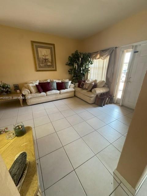 A living room features light-colored sofas, tile flooring, a large potted plant, and a doorway — 18201 SW 144th Ct, Miami FL 33177, MIAMI, FL