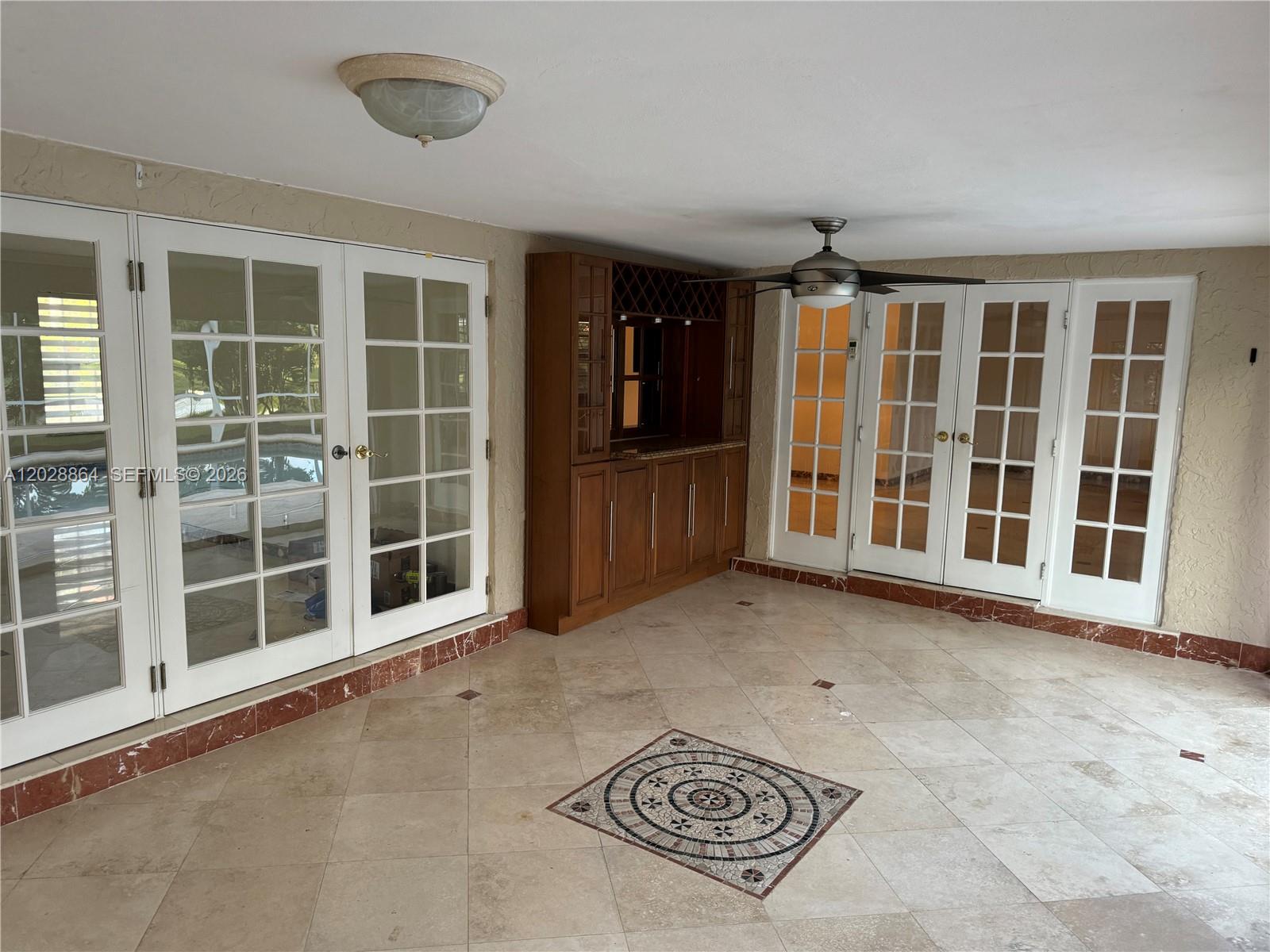 A sunroom features tile flooring with a mosaic inlay, a built-in bar, and French doors — WESTON, FL