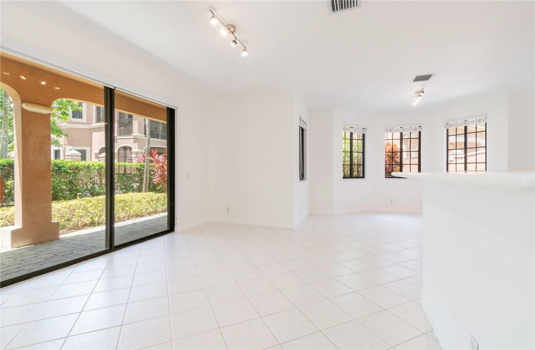 An empty room with white tile floors, sliding glass doors, and windows overlooking a patio — 2692 Center Ct Drive # 32, Weston FL 33332, WESTON, FL