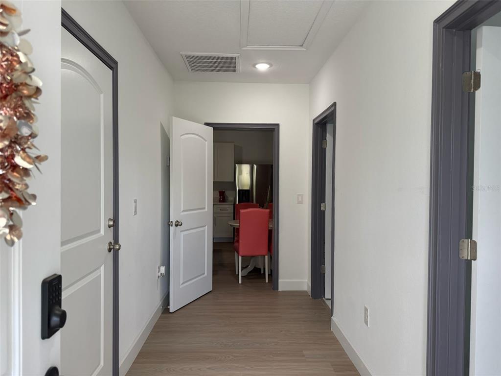 A hallway with light wood-look flooring leads to a doorway revealing a dining area — 2050 FLORIDA DEVELOPMENT ROAD UNIT B, DAVENPORT, FL