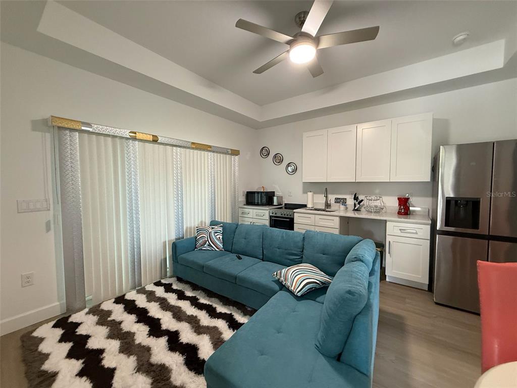 A living room features a blue sectional sofa, a patterned rug, and a kitchenette — 2050 FLORIDA DEVELOPMENT ROAD UNIT B, DAVENPORT, FL