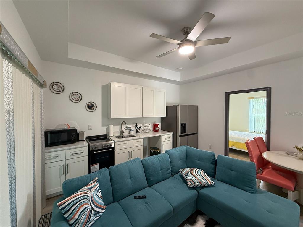 A small kitchen with white cabinets and a blue sectional sofa in an open-concept room — 2050 FLORIDA DEVELOPMENT ROAD UNIT B, DAVENPORT, FL