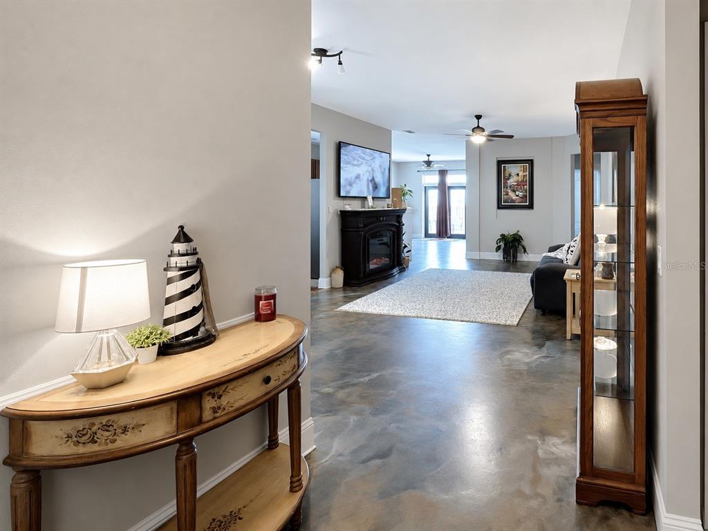 A foyer with a console table leads into a living room with polished concrete floors — 1012 SW 242ND TERRACE, NEWBERRY, FL