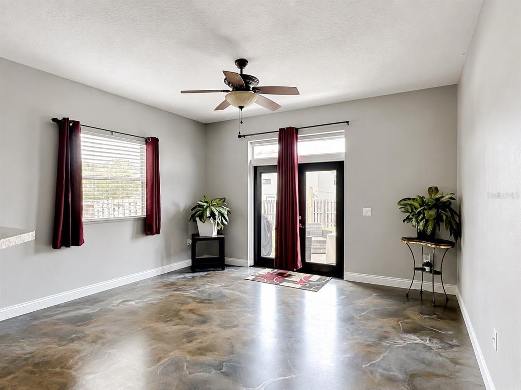 A living room features gray walls, a ceiling fan, dark curtains, and a polished concrete floor — 1012 SW 242ND TERRACE, NEWBERRY, FL