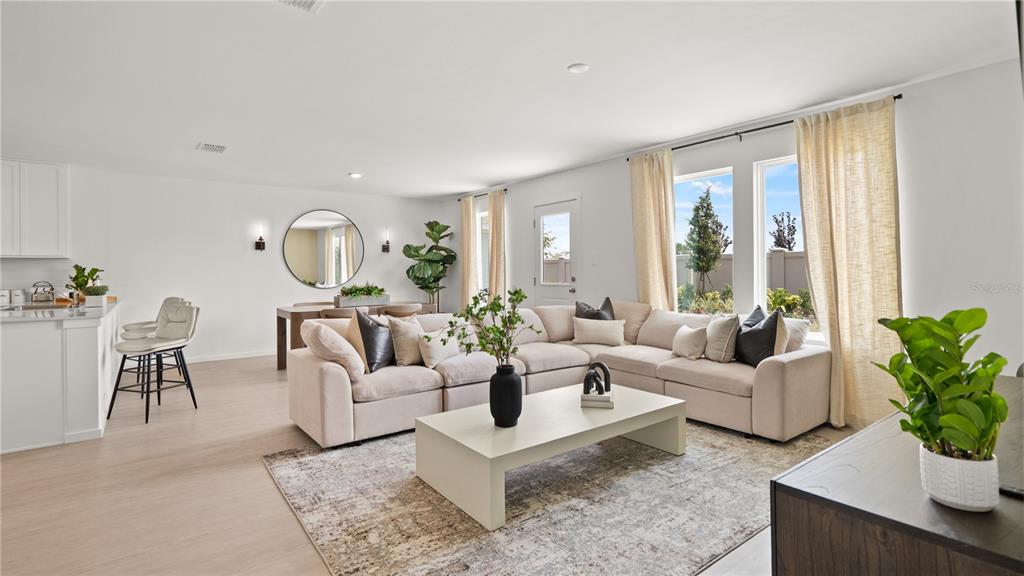 A bright, open-concept living room features a large beige sectional, coffee table, and dining area — 3416 ROVER ROAD, EAGLE LAKE, FL