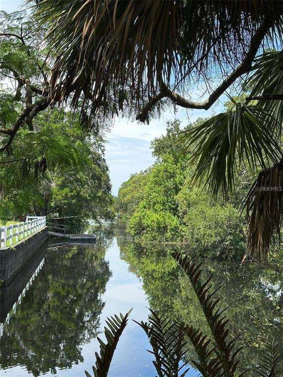 A view of a narrow canal lined with lush green trees and a white fence — 14569 and 0 CORAL DRIVE, HUDSON, FL