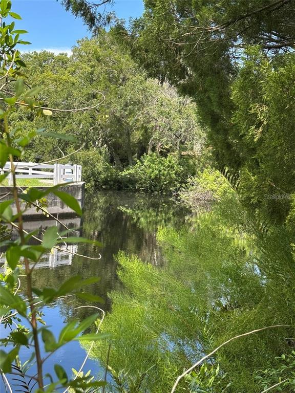 A view of a calm pond bordered by lush green trees and a white fence — 14569 and 0 CORAL DRIVE, HUDSON, FL