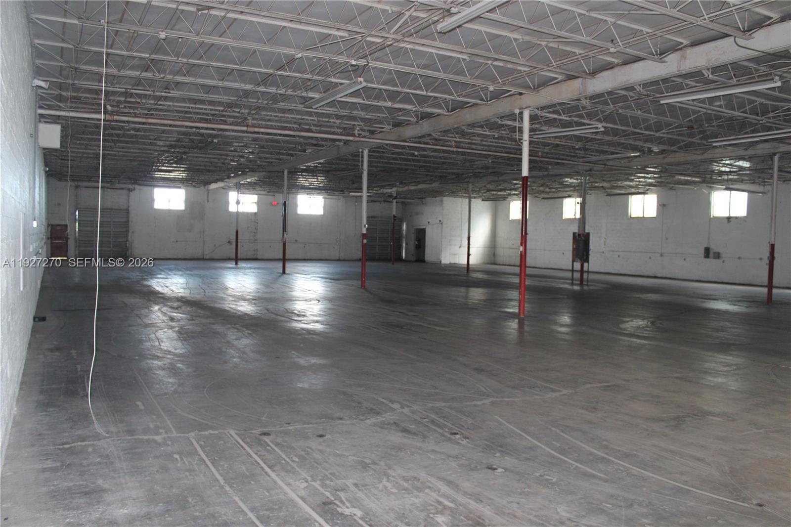 A large, open warehouse space features concrete floors, exposed ceiling trusses, and red support columns — 3121 E 11th Ave # 3121, Hialeah FL 33013, HIALEAH, FL