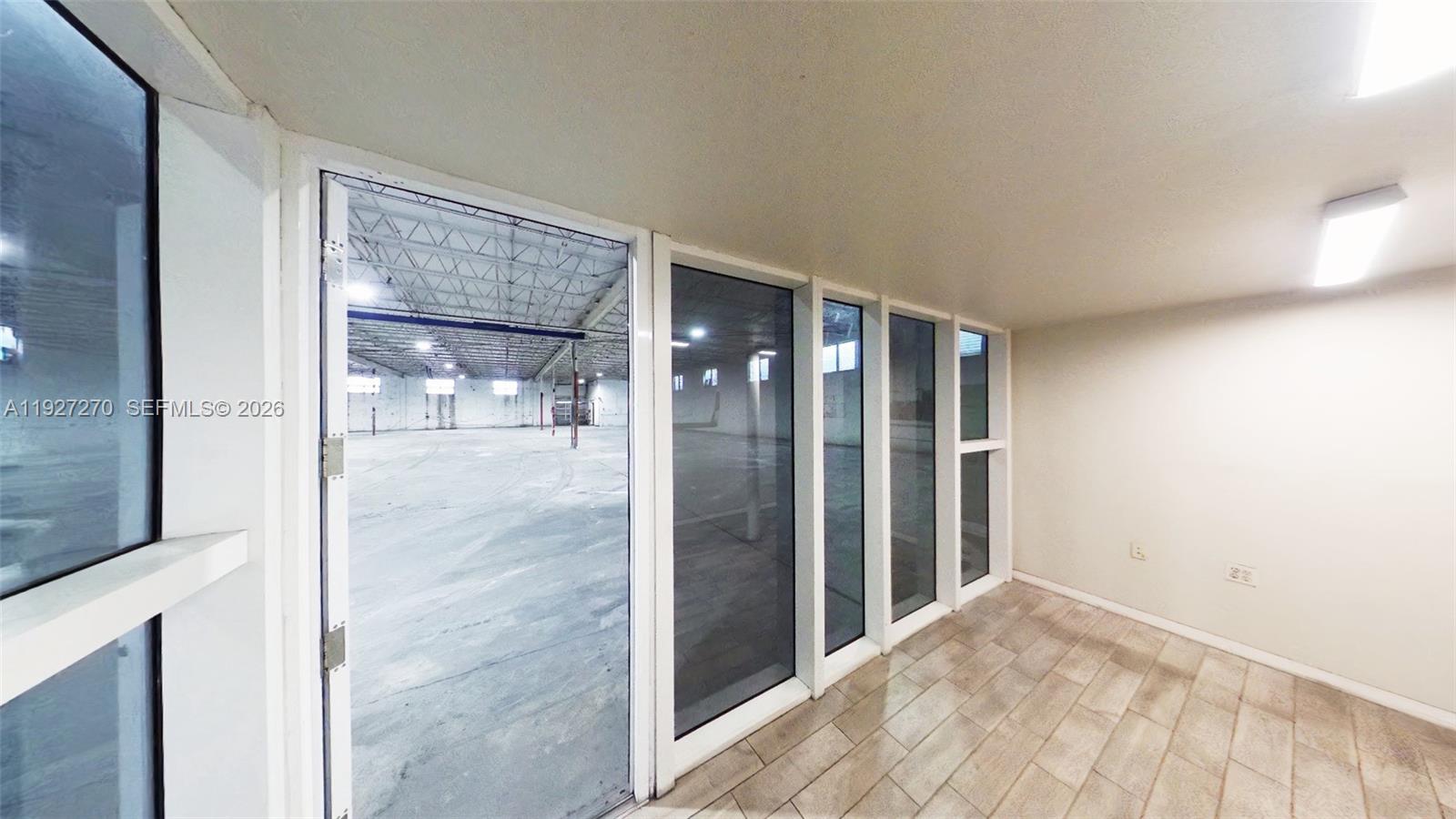 A small room with tiled flooring looks through glass walls into a large warehouse space — 3121 E 11th Ave # 3121, Hialeah FL 33013, HIALEAH, FL