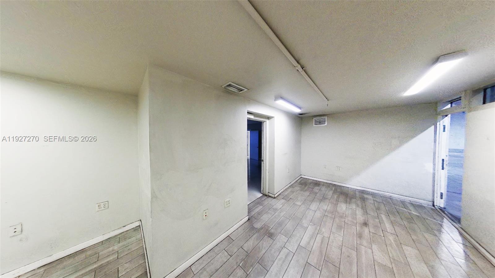 An interior room features light-colored walls, wood-look tile flooring, and two rectangular ceiling lights — 3121 E 11th Ave # 3121, Hialeah FL 33013, HIALEAH, FL