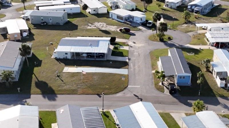 An aerial view shows several mobile homes with metal roofs and carports in a residential community — 6704 NEIGHBORLY COURT, NORTH PORT, FL