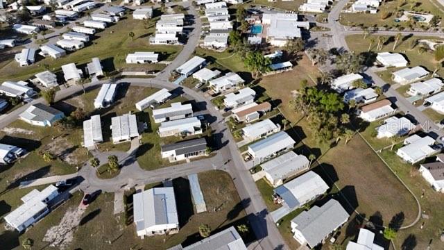 This aerial view shows a residential neighborhood with numerous manufactured homes and paved streets — 6704 NEIGHBORLY COURT, NORTH PORT, FL
