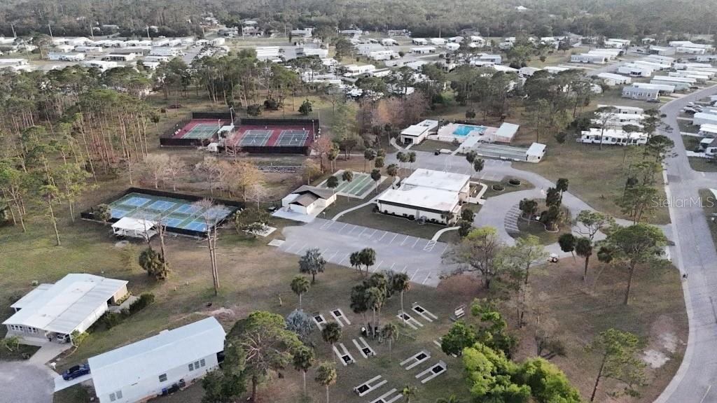 An aerial view shows a community center with tennis courts, a pool, and surrounding homes — 6704 NEIGHBORLY COURT, NORTH PORT, FL