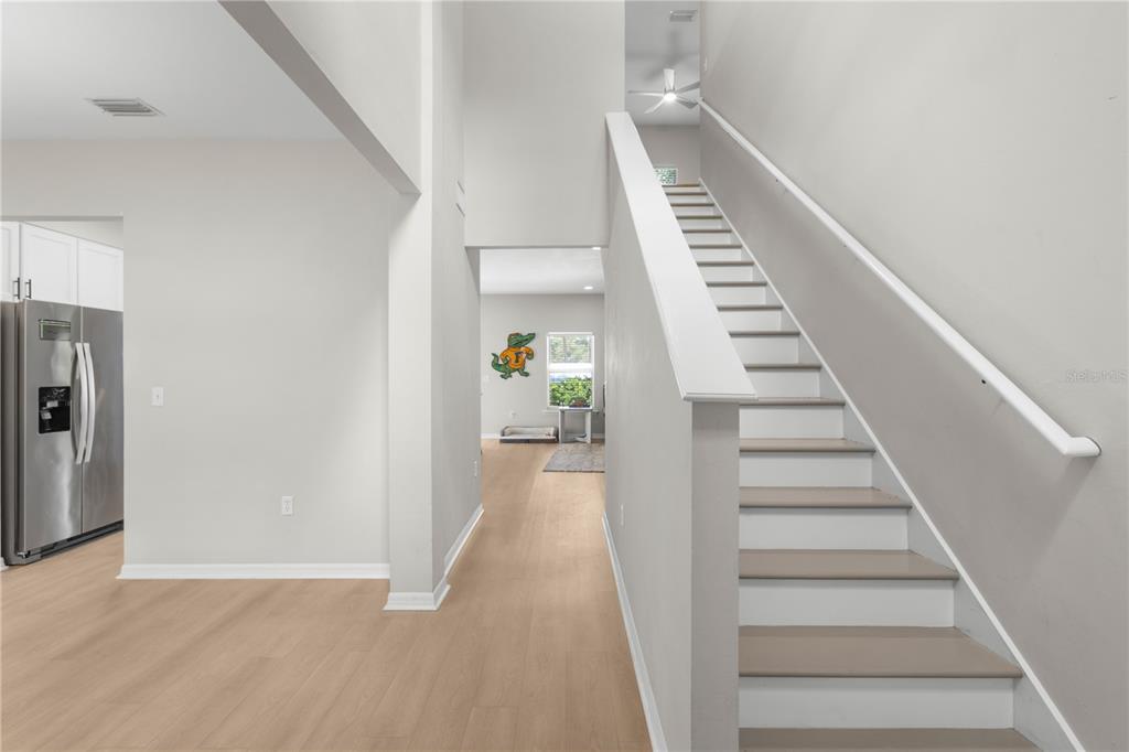 A view of a staircase, light wood flooring, and a glimpse into an adjacent room — 16 NW 29 STREET, GAINESVILLE, FL