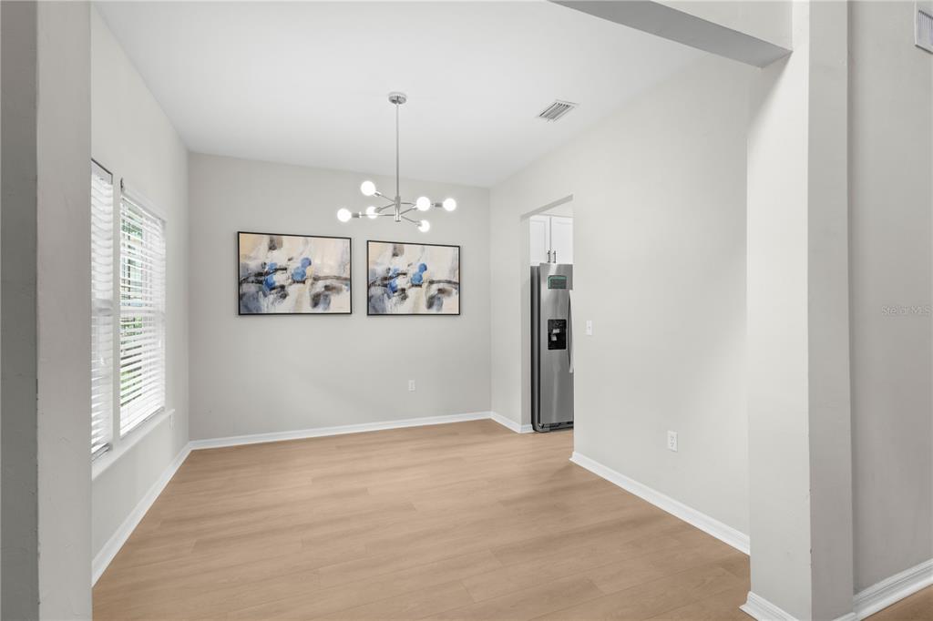 A dining area features light wood-look flooring, a modern chandelier, and two framed abstract artworks — 16 NW 29 STREET, GAINESVILLE, FL