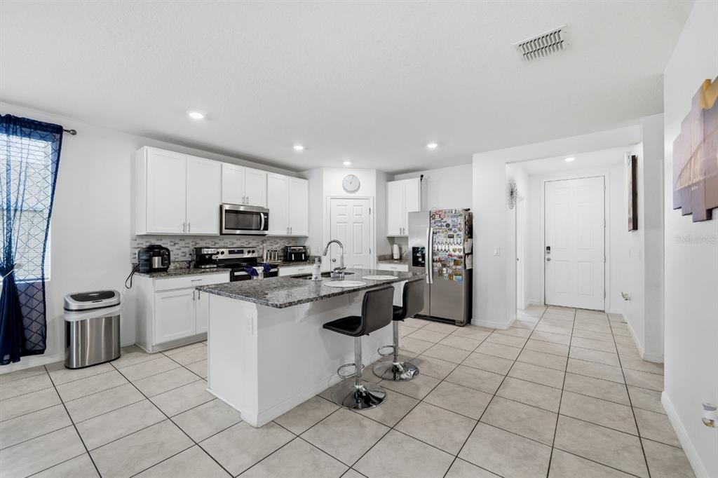A kitchen with white cabinets, granite countertops, a central island, and stainless steel appliances — 1036 KOBUK STREET, HAINES CITY, FL