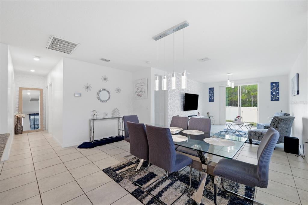 A dining area with a glass table and chairs sits in an open-concept living space — 1036 KOBUK STREET, HAINES CITY, FL