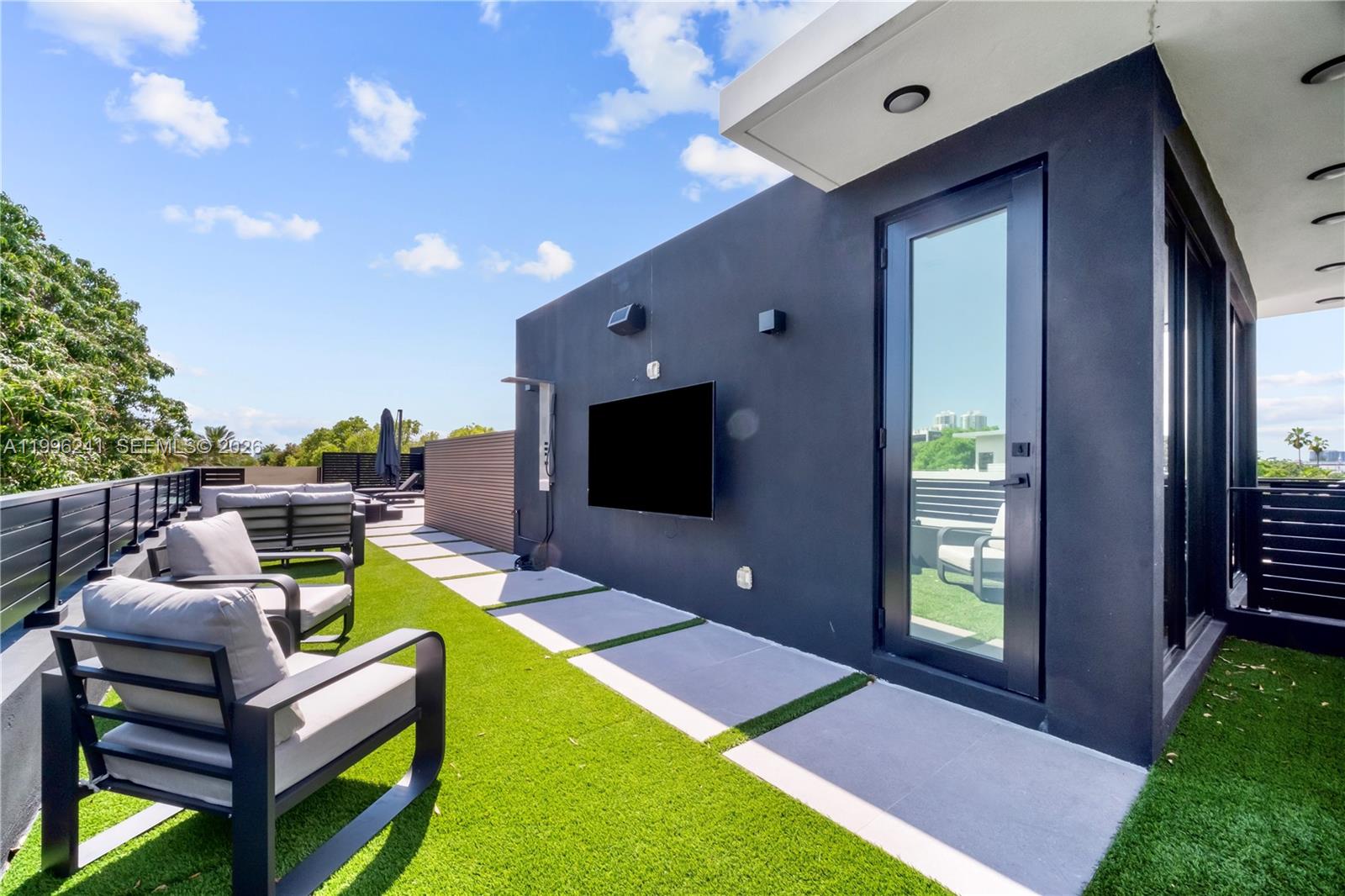 A modern rooftop terrace features artificial turf, concrete pavers, outdoor seating, and a wall-mounted television — 420 SW 15th Rd # 420, Miami FL 33129, MIAMI, FL