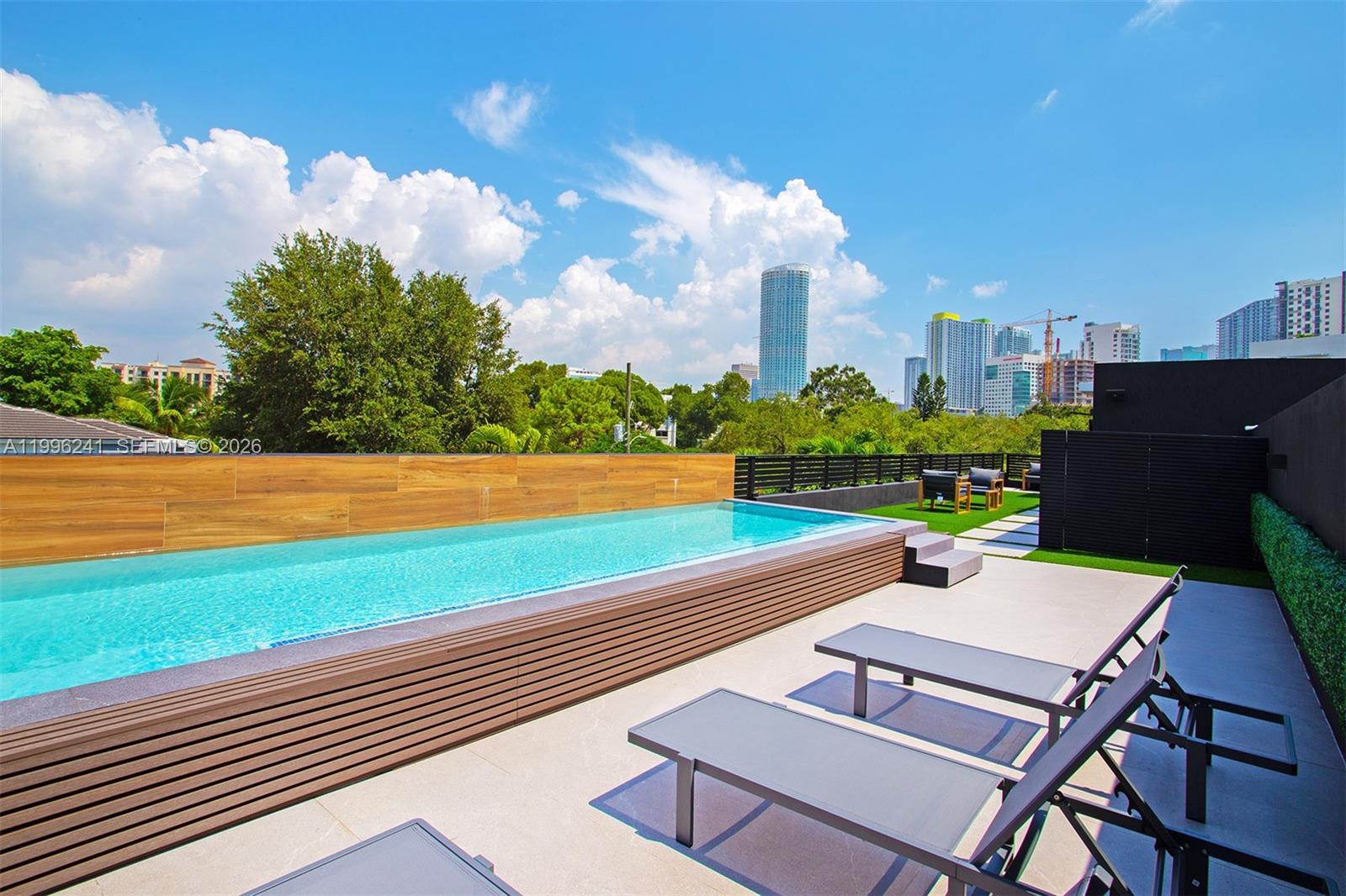 A rooftop terrace features a rectangular swimming pool, lounge chairs, and a city skyline view — 420 SW 15th Rd # 420, Miami FL 33129, MIAMI, FL