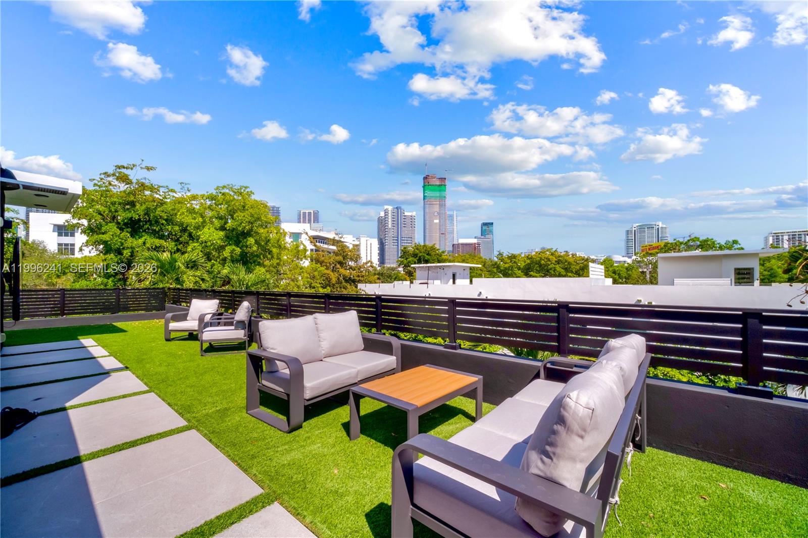 A rooftop terrace features artificial turf, modern patio furniture, and a view of city skyscrapers — 420 SW 15th Rd # 420, Miami FL 33129, MIAMI, FL