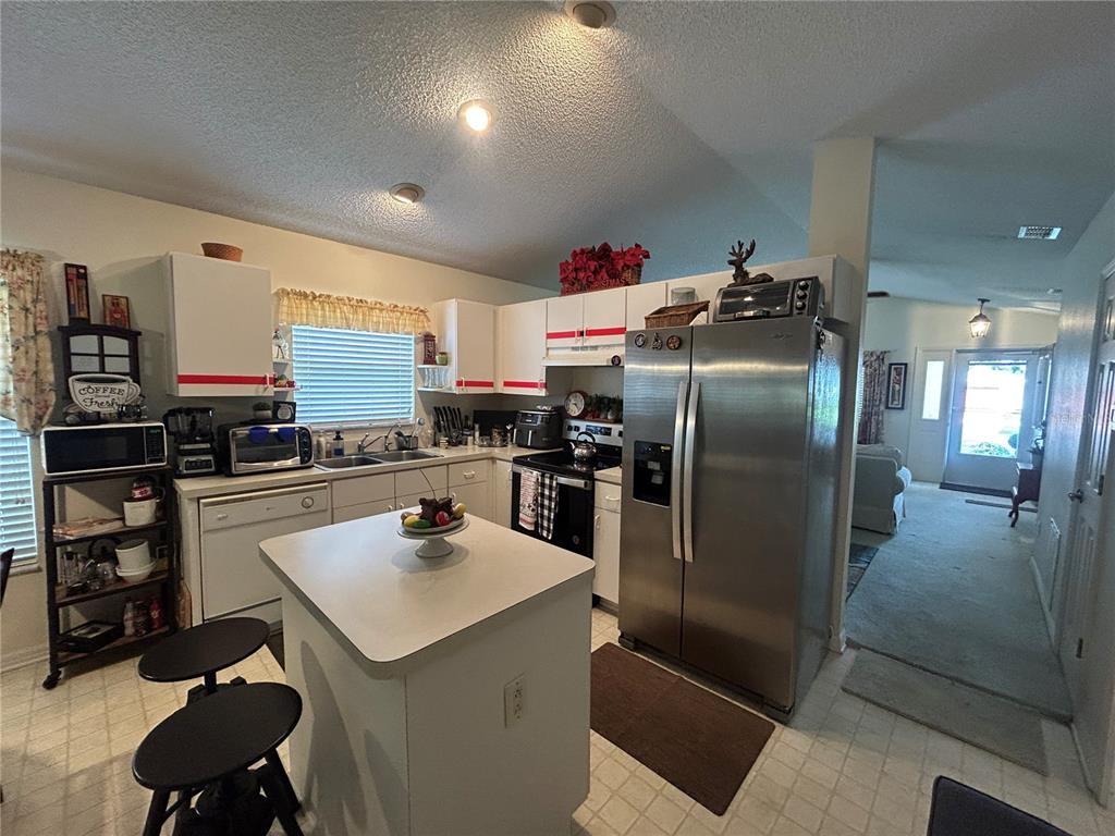 A kitchen features white cabinets with red trim, a center island, and stainless steel appliances — 25119 CRANES ROOST CIRCLE, LEESBURG, FL