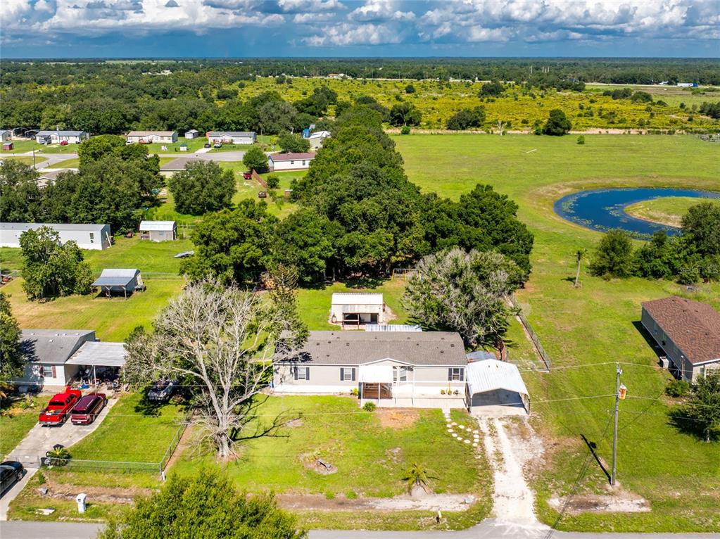 An aerial view shows a single-story house with a carport and outbuildings on a rural lot — 5635 SW BRAHMA AVENUE, ARCADIA, FL