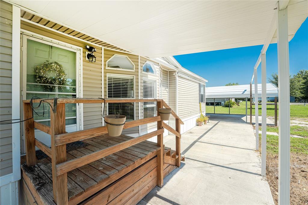 A wooden porch with a railing sits beside a mobile home under a covered patio — 5635 SW BRAHMA AVENUE, ARCADIA, FL