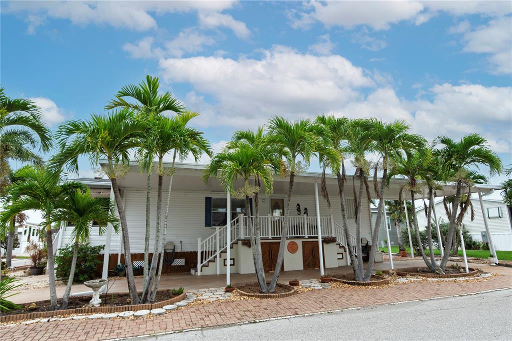 A white mobile home features a covered carport, a front porch, and several palm trees — 29 AMSTERDAM AVENUE, PUNTA GORDA, FL