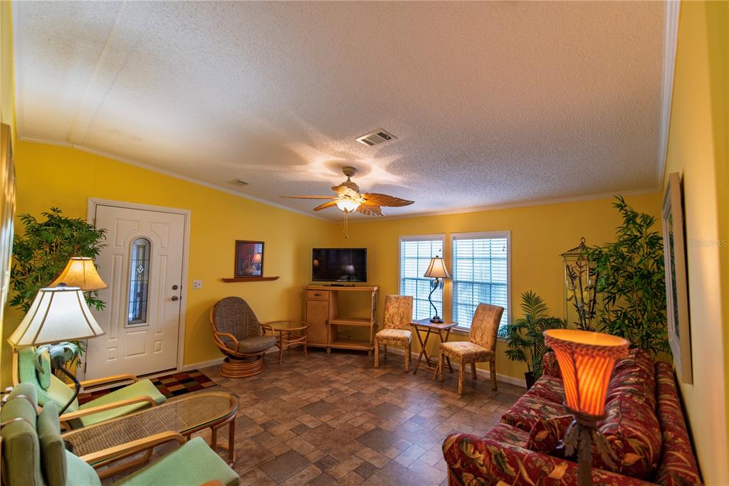 A living room with yellow walls, tile flooring, a ceiling fan, and various furniture pieces — 29 AMSTERDAM AVENUE, PUNTA GORDA, FL