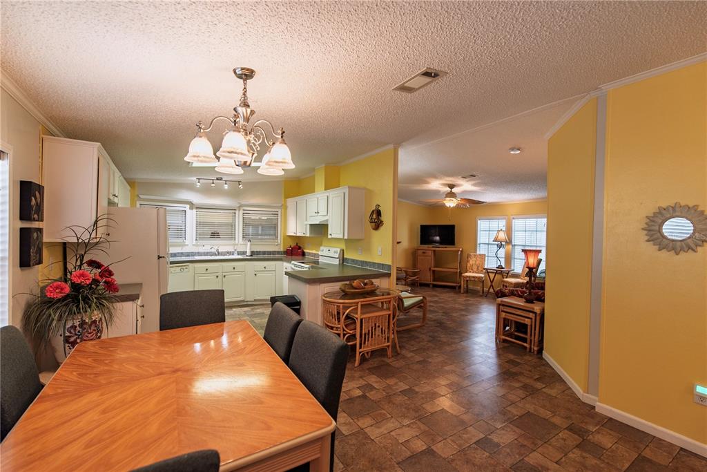 A dining area with a wooden table opens into a kitchen and living room space — 29 AMSTERDAM AVENUE, PUNTA GORDA, FL