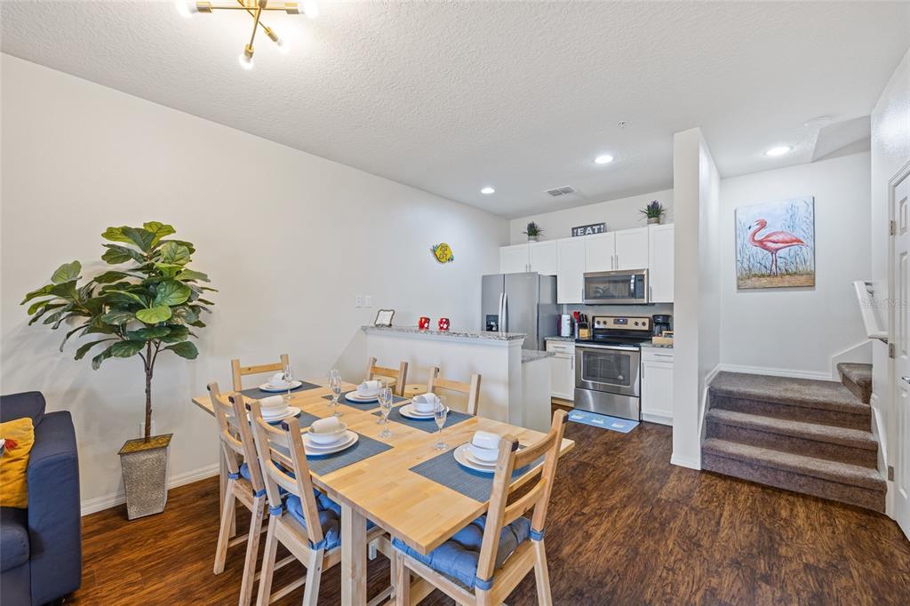 A dining area with a wooden table and chairs sits adjacent to a modern kitchen — 8945 SHINE DRIVE, KISSIMMEE, FL