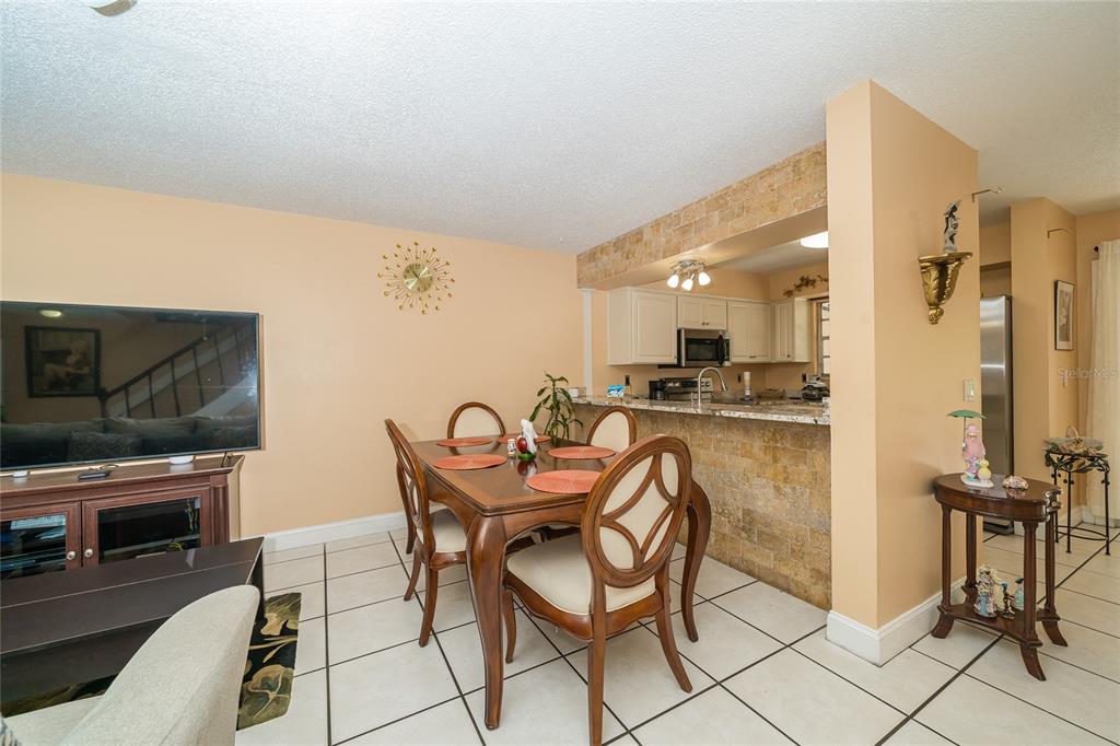 A dining area with a wooden table, chairs, and a breakfast bar with stone accents — 14015 LEMON VALLEY PLACE, TAMPA, FL