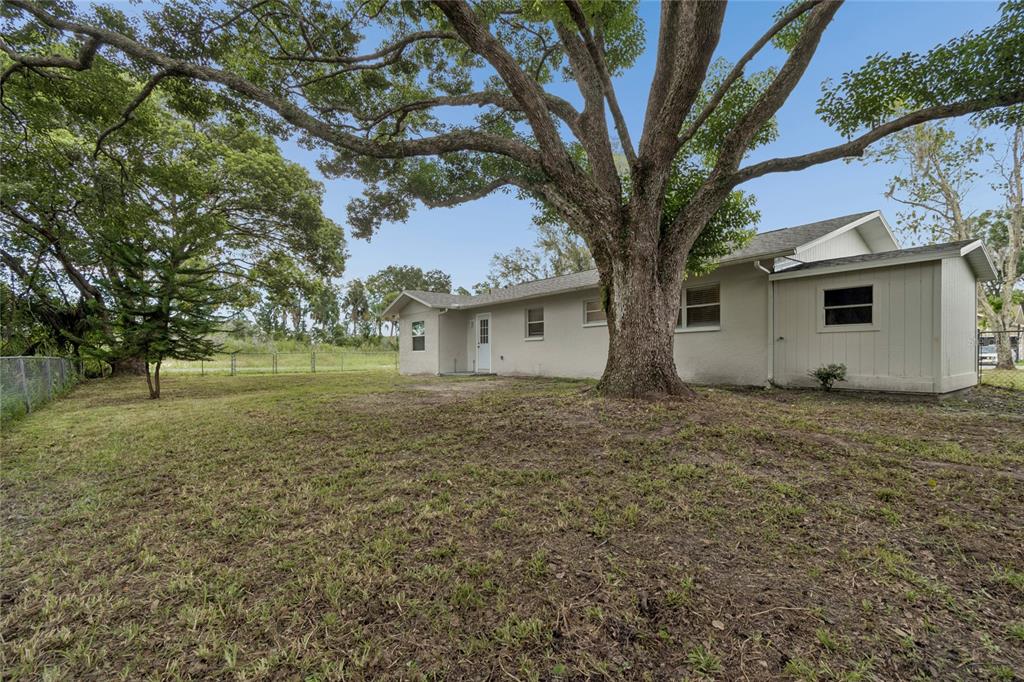 The exterior of a single-story house features a large tree in the backyard — 7949 KNIGHT DRIVE, NEW PORT RICHEY, FL