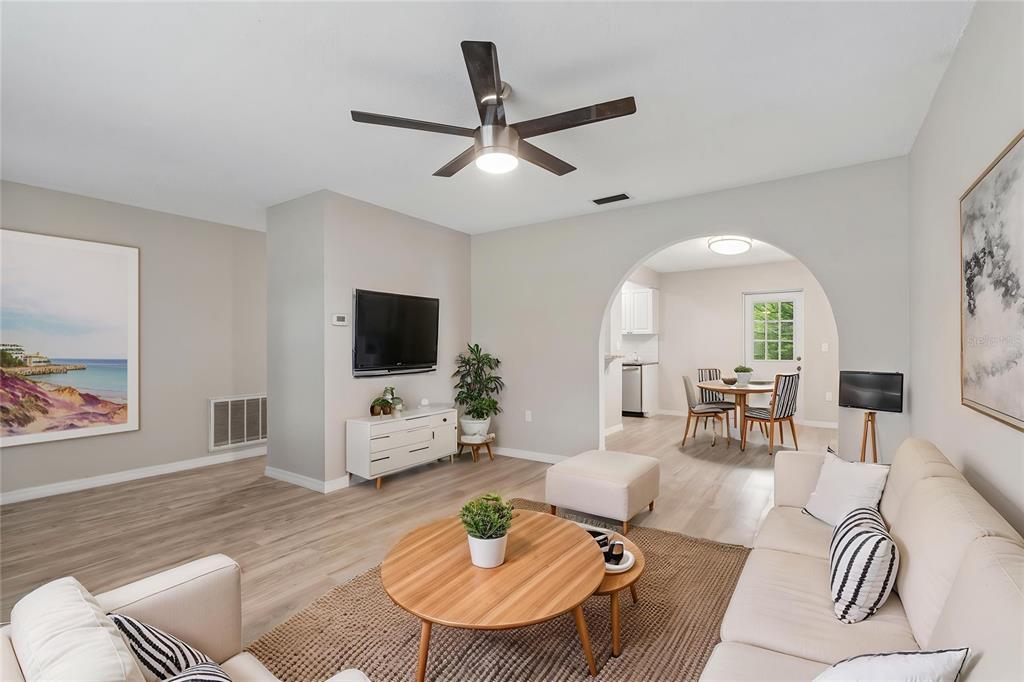 A living room with light wood floors, a ceiling fan, and an arched entryway to a dining area — 7949 KNIGHT DRIVE, NEW PORT RICHEY, FL