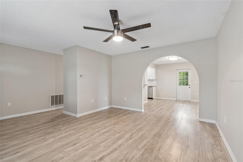 A living room with light wood-look flooring, a ceiling fan, and an arched entryway — 7949 KNIGHT DRIVE, NEW PORT RICHEY, FL