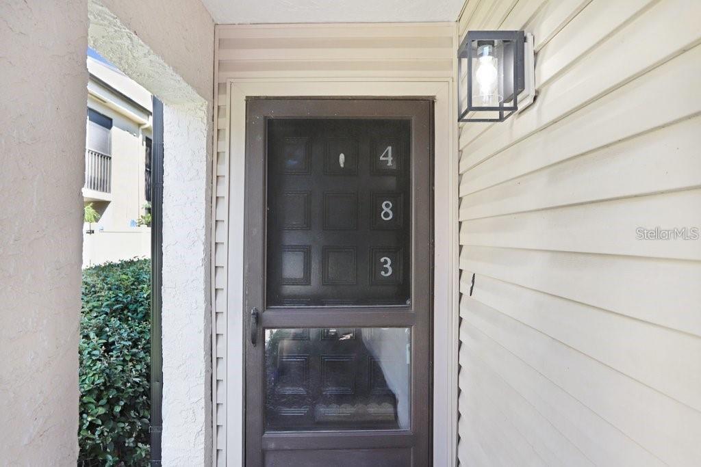 A brown storm door with the numbers 483 is mounted on a light-colored exterior wall — 4833 PURITAN CIRCLE UNIT 101, TAMPA, FL