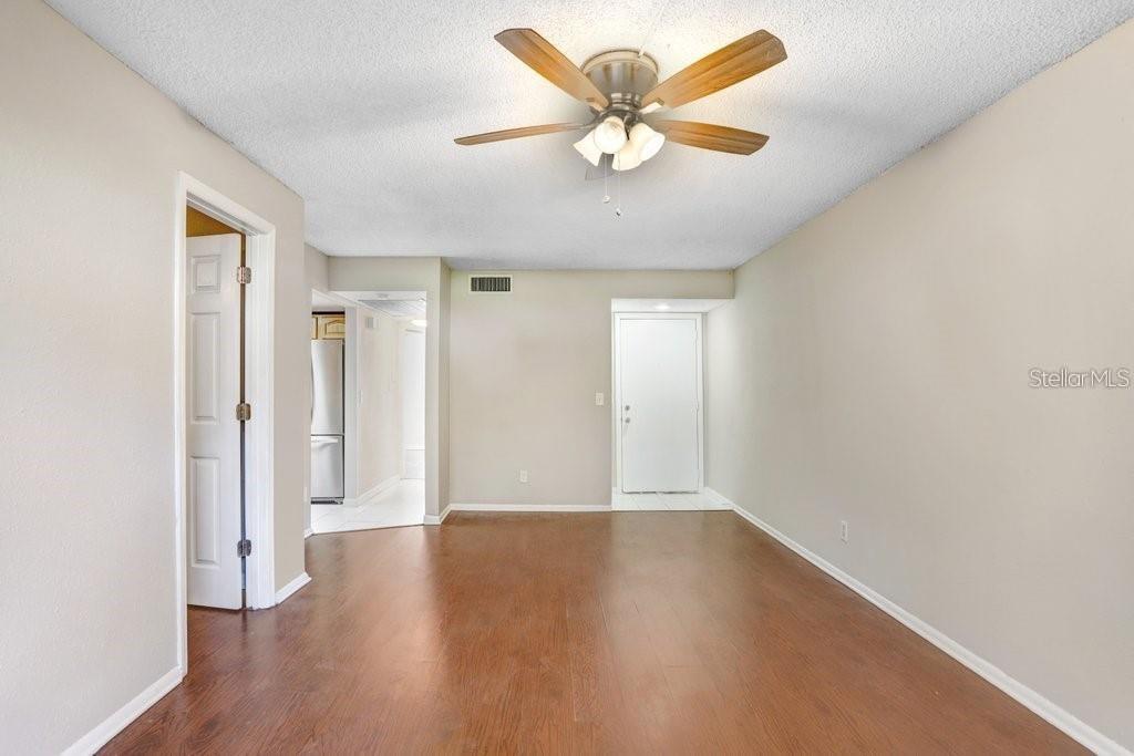 An empty room with wood-look flooring, a ceiling fan, and a white door — 4833 PURITAN CIRCLE UNIT 101, TAMPA, FL