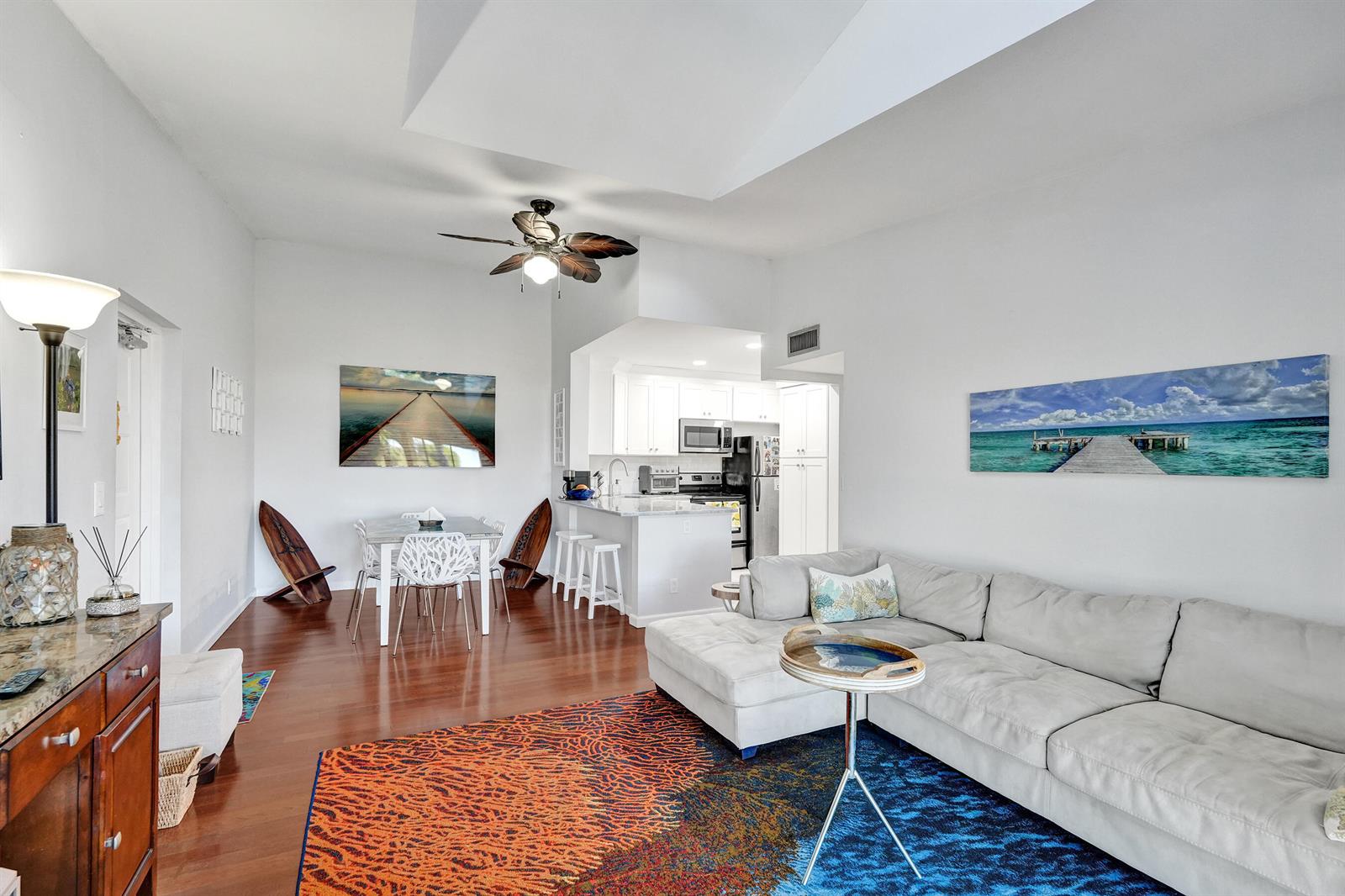 A living room and dining area with hardwood floors, a sectional sofa, and white cabinetry — 1008 Green Pine Boulevard # D3, West Palm Beach FL 33409, WEST PALM BEACH, FL